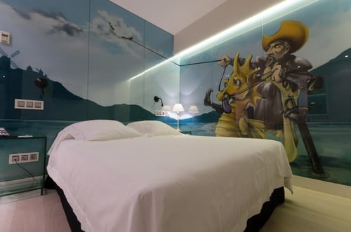 A room with walls decorated with murals inspired by Don Quixote, featuring an illustration of an armed man on horseback. The